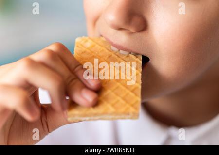 Gros plan d'une femme méconnaissable mordant une gaufre. Dessert sucré. Photo de haute qualité Banque D'Images