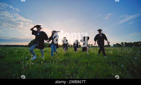 Les diplômés de l'université courent au coucher du soleil dans la soirée. Banque D'Images