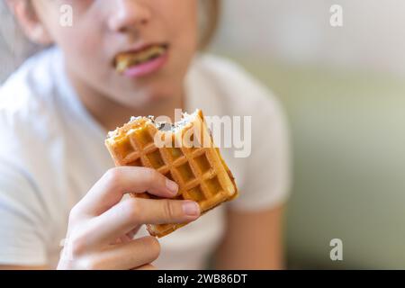 Gros plan d'une femme méconnaissable mordant une gaufre. Dessert sucré. Banque D'Images