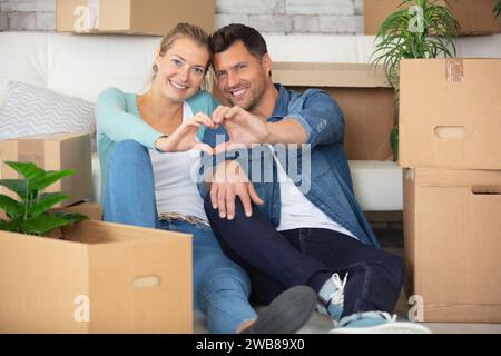 couple faisant des formes de coeur avec leurs mains dans la nouvelle maison Banque D'Images