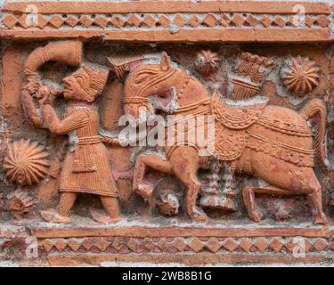 Vue en gros plan de la scène en terre cuite sculptée avec le cheval et l'homme soufflant la corne sur l'ancien temple Govinda dans le complexe religieux Puthia, Rajshahi, Bangladesh Banque D'Images