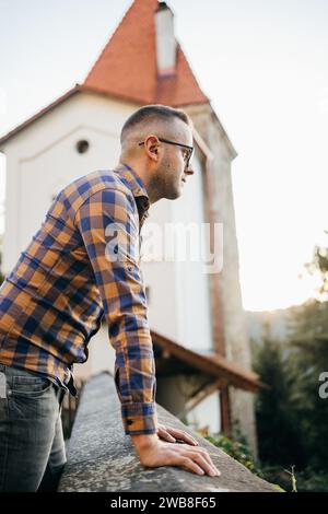 Jeune homme en chemise et s'appuie contre le mur du château lors d'un voyage Banque D'Images