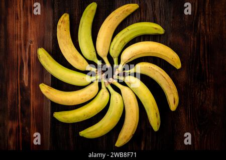 Bananes sur table en bois brun vue de dessus. Position figurée des bananes en forme géométrique. les bananes sont disposées en forme de soleil. Banque D'Images