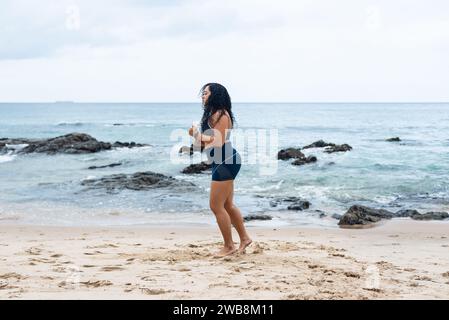 Portrait de belle femme de fitness faisant des étirements sur le sable de plage. Mode de vie sain. Banque D'Images