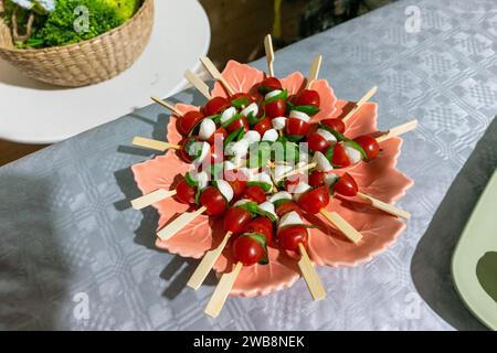 Brochettes de tomates cerises vibrantes avec fromage frais et basilic, un ajout exquis à tout rassemblement festif. Banque D'Images