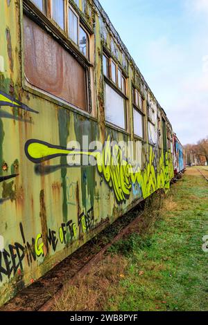 AS, Limbourg, Belgique. 17 décembre 2023. Perspective latérale de très vieille voiture de tourisme verte peinte avec des graffitis, métal corrodé et rouillé, tra désaffecté Banque D'Images