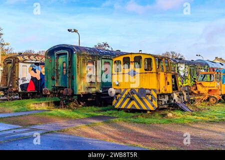 AS, Limbourg Belgique. 17 décembre 2023. Wagons abandonnés, en ruines, avec graffitis et rouillés par le passage du temps sur des voies désaffectées contre blu Banque D'Images