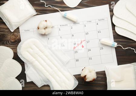 Calendrier menstruel avec tampons de coton et serviettes sur fond brun. Vue de dessus Banque D'Images