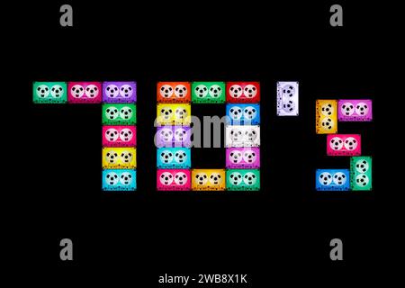 Texte carré '70' sur fond noir isolé, composé de cassettes audio anciennes, différentes et colorées. L'année de la nostalgie pour le hom analogique Banque D'Images