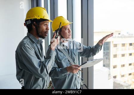 Travailleur de la construction utilisant le talkie-walkie pour contrôler le travail sur le chantier de construction Banque D'Images