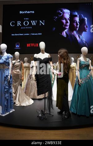 Une assistante de galerie ajuste une reproduction de la robe de revanche de la princesse Diana, qui fait partie de la collection de plus de 450 costumes, décors et accessoires de la série Netflix The Crown, présentée à Bonhams dans le centre de Londres, avant d'être vendue aux enchères le mois prochain. Date de la photo : mardi 9 janvier 2024. Banque D'Images