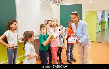 Enseignante distribuant des livres aux élèves debout dans la salle de classe Banque D'Images