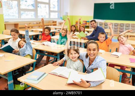 Portrait de professeur d'école primaire assis avec des écoliers dans la salle de classe Banque D'Images