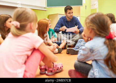 Enseignant discutant avec un groupe d'étudiants assis sur le sol dans la salle de classe Banque D'Images