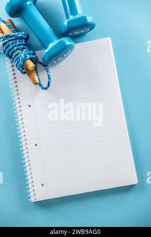 Un cahier vide, des haltères bleus et une corde à sauter le conduisaient. Concept de sport et de mode de vie sain. Banque D'Images