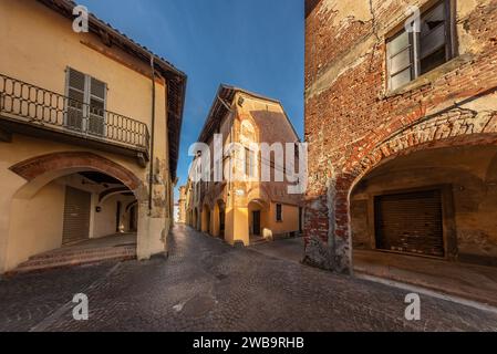 Carignano, Turin, Italie - 11 novembre 2023 : vieilles maisons avec arcades sur la via Vittorio Veneto dans le quartier d'origine médiévale appelé Isola di San Gio Banque D'Images