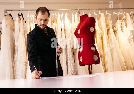 Tailleur masculin ou couturière prenant des mesures de mannequin pour le modèle de tissu avec ruban à mesurer dans le studio de design de mode, designer femme travaillant avec du Banque D'Images