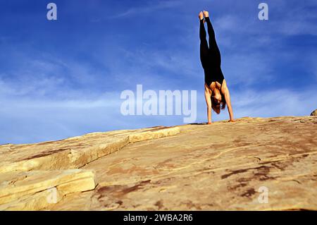 Une femme athlétique faisant un stand au-dessus d'une formation rocheuse de grès dans la zone de loisirs Red Rocks du Nevada Banque D'Images