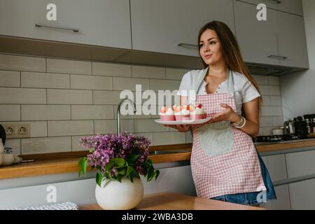 Femme préparant savoureux cupcake de Pâques dans la cuisine. Banque D'Images