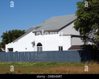 Miami, Floride, États-Unis - 31 décembre 2023 : Maison blanche avec tuiles grises et clôture grise à l'ouest de Miami. Banque D'Images