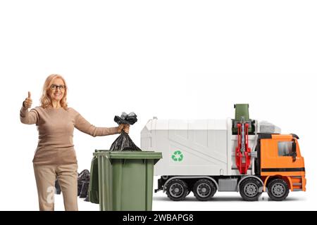 Femme devant un camion garabe jetant un sac de déchets dans une poubelle et faisant des gestes pouces vers le haut isolé sur fond blanc Banque D'Images