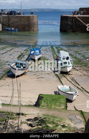 De petits bateaux échouent dans le port de Mousehole à marée basse Cornwall England Banque D'Images