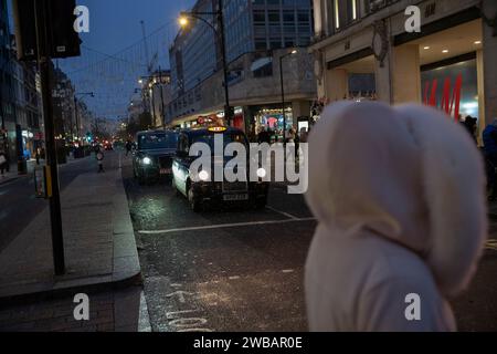 Les acheteurs bravent le froid hivernal pendant les averses glaciales et les averses de pluie sur Oxford Street, la rue la plus fréquentée de Londres, en Angleterre, au Royaume-Uni Banque D'Images