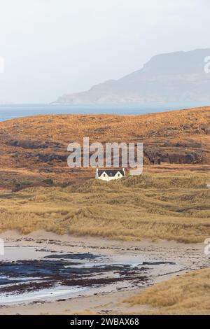 Une maison isolée à Sanna sur la péninsule d'Ardnamurchan avec l'île d'Eigg en arrière-plan. Banque D'Images