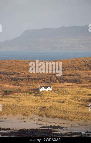 Une maison isolée à Sanna sur la péninsule d'Ardnamurchan avec l'île d'Eigg en arrière-plan. Banque D'Images