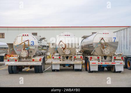 Rangée de trois camions-citernes en métal brillant utilisés pour transporter du carburant. Banque D'Images