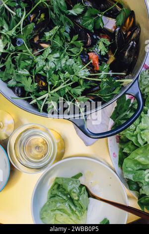 Vue grand angle de moules Mariniere sur table dorée, moules cuites à la vapeur dans une casserole avec du vin blanc, du persil italien Banque D'Images
