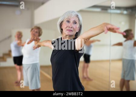 Femme âgée qui s'échauffe pendant l'entraînement de groupe Banque D'Images