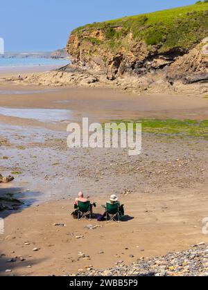 Deux personnes assises dans des transats seuls sur la plage de Little Haven South Wales Banque D'Images