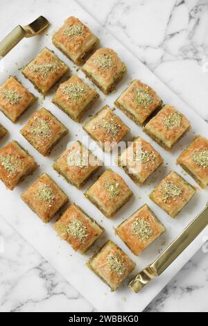 Délicieux baklava frais avec des noix hachées sur la table en marbre blanc, vue de dessus. Bonbons orientaux Banque D'Images