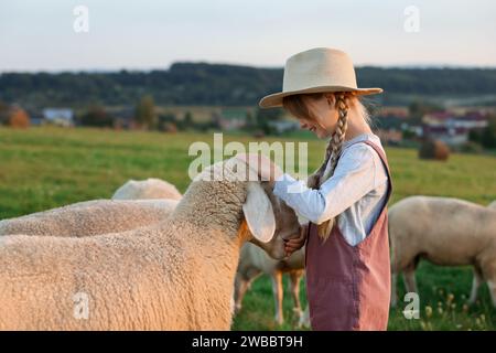 Fille nourrissant des moutons sur le pâturage. Animaux de ferme Banque D'Images