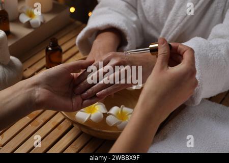 Femme recevant un traitement de la main à la table en bois dans le spa, closeup Banque D'Images