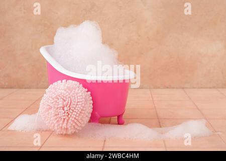 Petite baignoire avec mousse et éponge sur fond de couleur Banque D'Images
