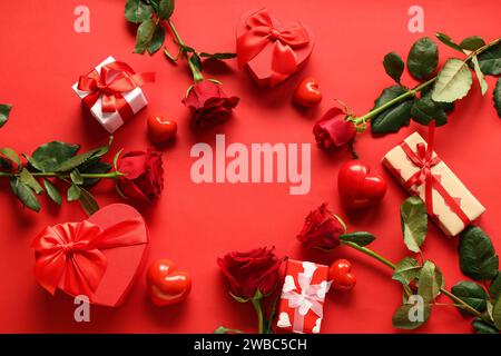 Cadre fabriqué à partir de belles roses, coeurs et boîtes-cadeaux sur fond rouge. Fête de la Saint-Valentin Banque D'Images