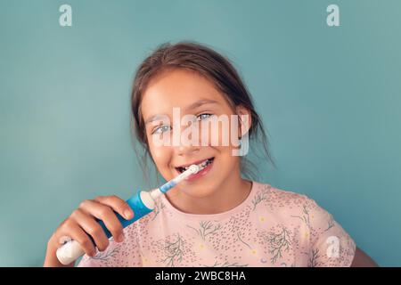 Portrait de beauté de joyeux joyeux positif belle fille, jeune adolescent se brosse ses dents blanches saines avec brosse à dents électrique avec dentifrice, lo Banque D'Images