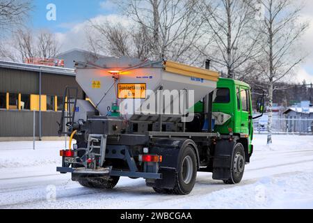 Camion de grincement Volvo FL6 épandage de gravier sur route glacée et enneigée par une journée froide de l'hiver, vue arrière. Salo, Finlande. 27 décembre 2023. Banque D'Images