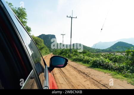 Vue depuis le pare-brise de la voiture depuis le siège conducteur. Voyagez au printemps ou en été. Belle vue du rétroviseur latéral de la voiture. Dirty Rural Road dans le sud Banque D'Images