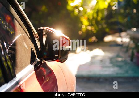 Le soleil brille sur le rétroviseur latéral de la voiture. La lumière du soleil se reflète sur le rétroviseur latéral d'une voiture garée. Banque D'Images