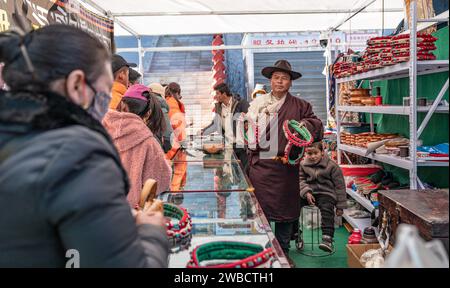 Lhassa, la région autonome chinoise de Xizang. 9 janvier 2024. Un vendeur fait la promotion de coiffures tibétaines traditionnelles sur un marché de Xigaze, dans la région autonome de Xizang, dans le sud-ouest de la Chine, le 9 janvier 2024. Les habitants de Xigaze célèbrent le nouvel an des agriculteurs le premier jour du douzième mois du calendrier tibétain, qui tombe le 12 janvier de cette année. À l'approche du festival, les rues et les marchés de Xigaze dégagent une atmosphère joyeuse et festive. Crédit : Tenzin Nyida/Xinhua/Alamy Live News Banque D'Images