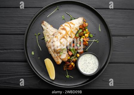 Filet de perche grillé servi sur une assiette sur un fond en bois sombre. Vue de dessus, pose à plat. Banque D'Images