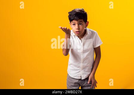 Portrait de garçon d'enfant surpris sur fond jaune. Étonné de l'expression faciale choquée, ouvrant largement la bouche et tenant les mains sur ses joues Banque D'Images