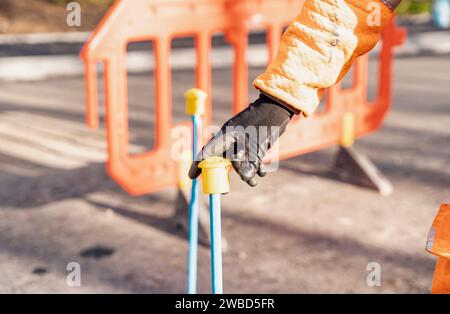 Constructeur plaçant des capuchons de protection de sécurité en plastique jaune sur le dessus de la route en posant des goupilles en acier sur un projet d'amélioration de la route Banque D'Images