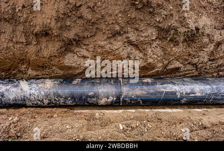 Nouvelle conduite d'eau en plastique dans la tranchée. Remplacement des vieux tubes rouillés par un nouveau Banque D'Images