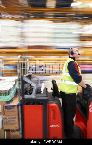 Homme sur camion se déplaçant dans un entrepôt de distribution moderne, dans le sud-est de l'Angleterre, Royaume-Uni Banque D'Images