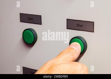 Le pouce de la main d'un homme appuie sur le bouton vert « Démarrer » en gros plan Banque D'Images