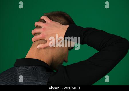 Émotions d'un beau gars homme sur un fond vert chromakey close-up cheveux foncés jeune homme Jeune homme d'affaires sur un bureau, avec une expression ennuyée. Photo de haute qualité Banque D'Images